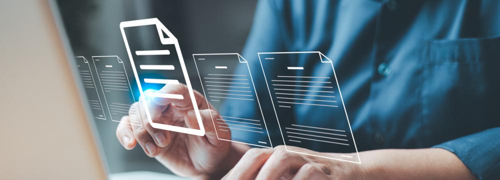 Une personne vêtue d'une chemise bleue à boutons tape sur un ordinateur portable sur lequel sont superposés des graphiques numériques représentant des documents et des dossiers.
