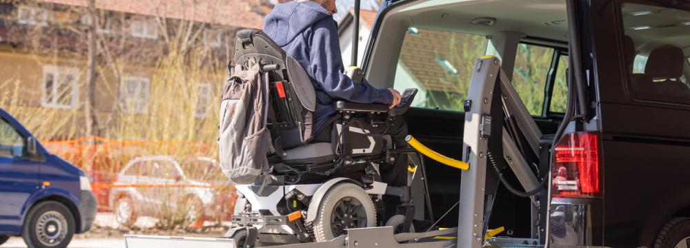 Un élévateur de fauteuil roulant soulève une personne en fauteuil roulant à l’intérieur d’un fourgon.