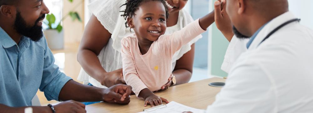 A joyous child with parents sitting across from a doctor in a medical office