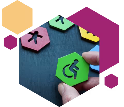 A hand arranging colourful hexagon blocks with accessibility and inclusion icons, including a green wheelchair symbol on a dark blue background.